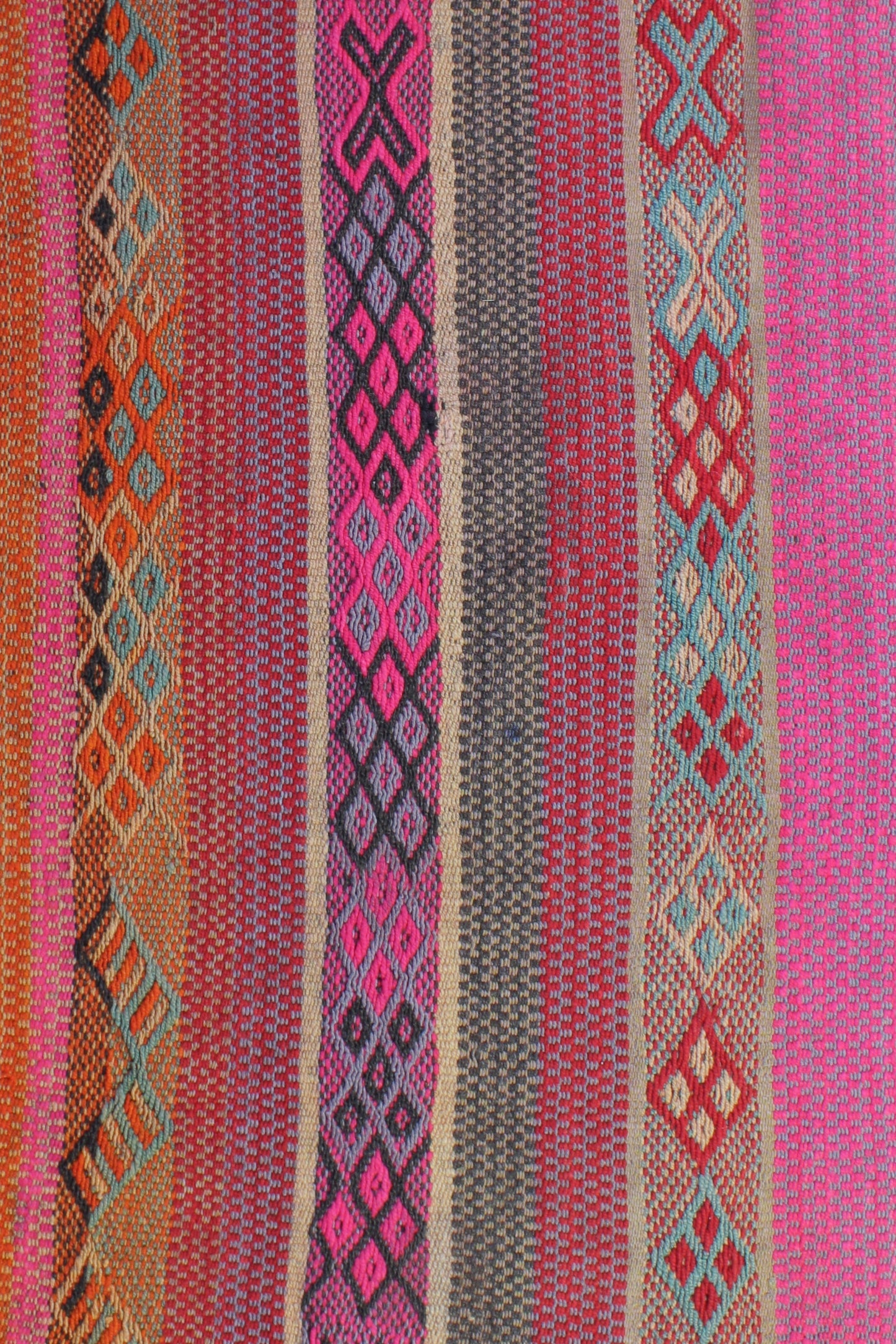 Lichtdurchfluteter Boho-Flur mit warmem Holzboden. Ein peruanischer Frazada-Teppich in Rosa- und Orangetönen mit leichten Asymmetrien liegt mittig. Holzbank, Pflanze und schlichte Deko ergänzen den Raum. Natürliches Licht wirkt weich und harmonisch.