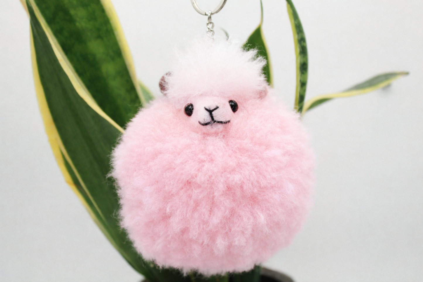 Pinker Alpaka Schluesselanhaenger mit Metallring im Wohnraum