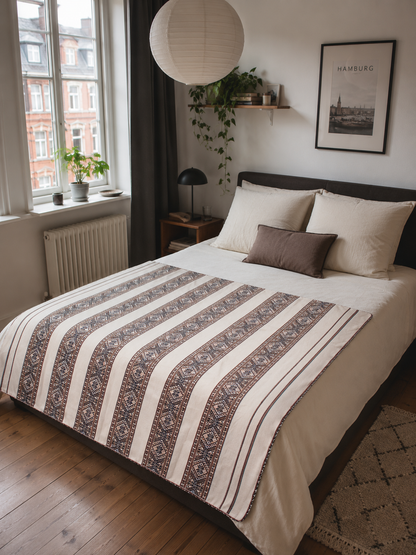 Handgewebte Tagesdecke aus Peru aus hochwertiger Baumwolle mit traditionellem Andenmuster auf einem Bett in einer Hamburger Altbauwohnung. Authentische Boho-Dekoration und nachhaltiges Kunsthandwerk.