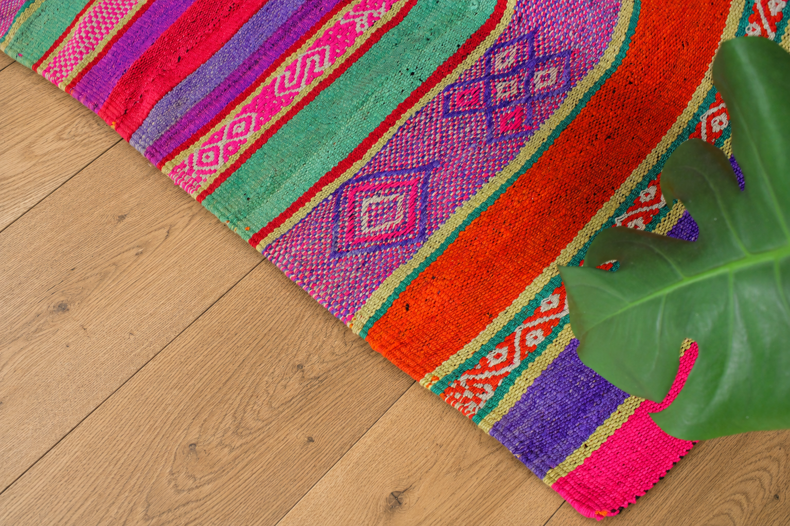 Bunter handgewebter Peruanischer Frazada Teppich aus Schafwolle im Boho-Wohnzimmer auf Holzboden – traditioneller Anden Teppich mit kräftigen Farben, authentischer Struktur und ethnischem Muster.