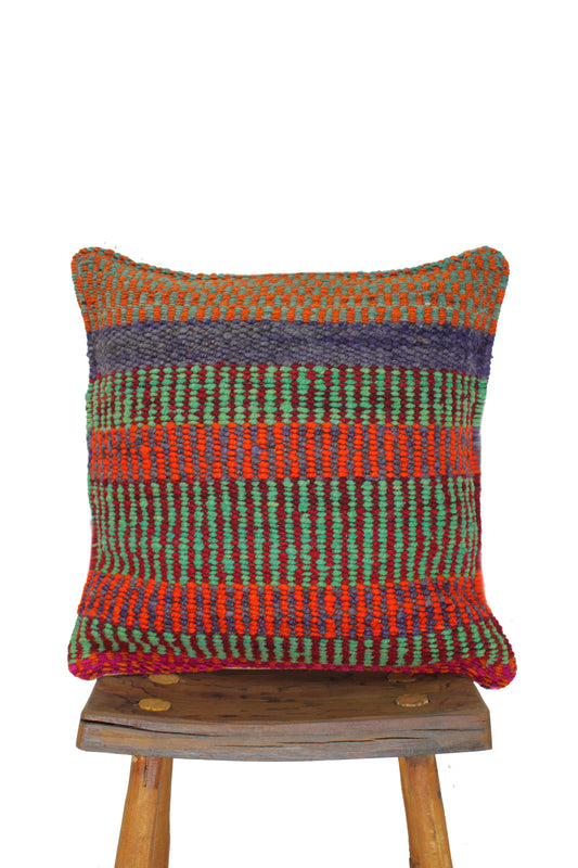 Grünes Frazadakissen 45x45 aus Peru von Glueck & Fund, weiches Textil mit traditionellem Muster, auf einem Sofa liegend