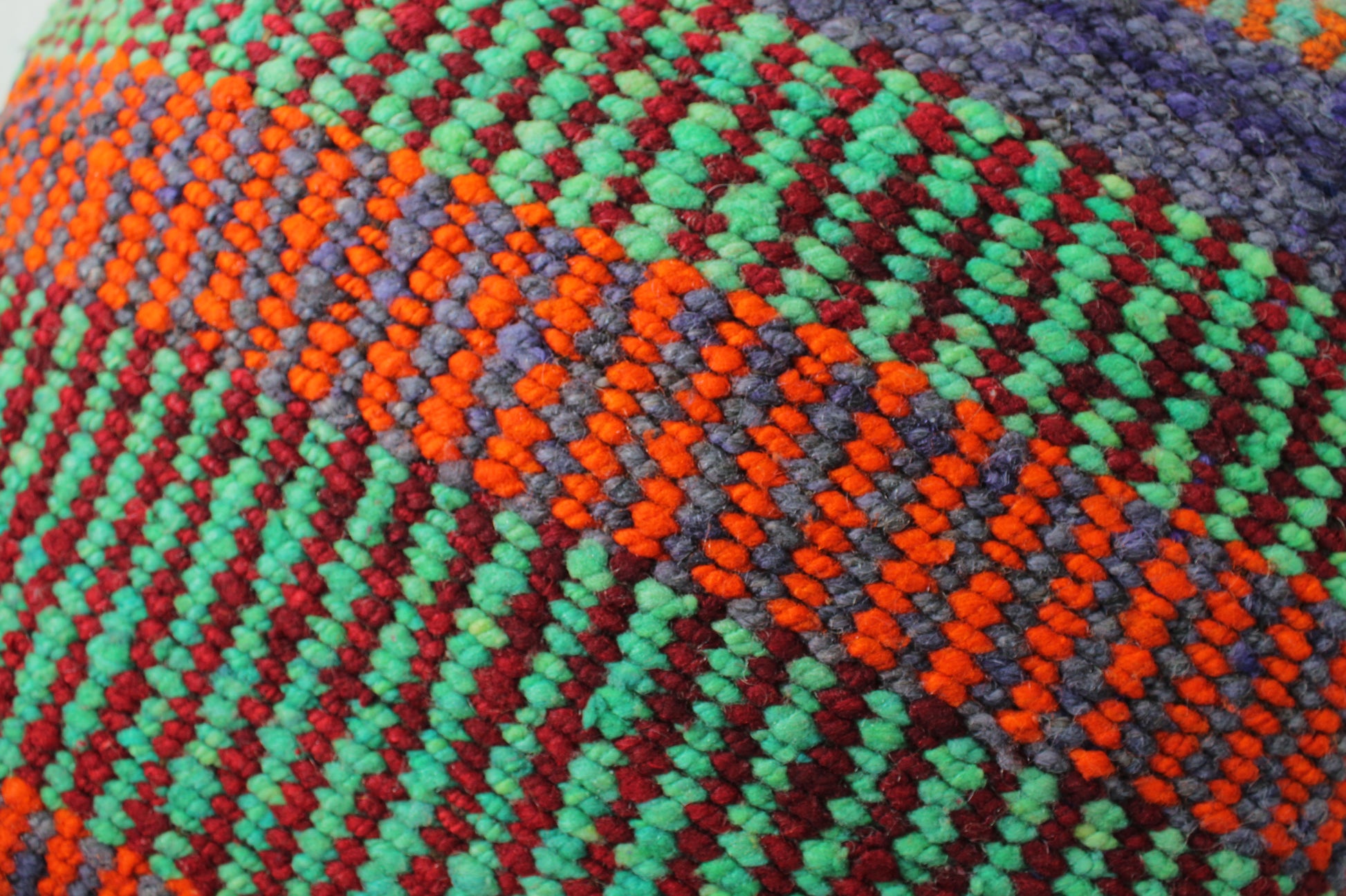 Grünes Frazadakissen 45x45 aus Peru von Glueck & Fund, weiche Textur und handgefertigtes Design, liegt auf einem Sofa.