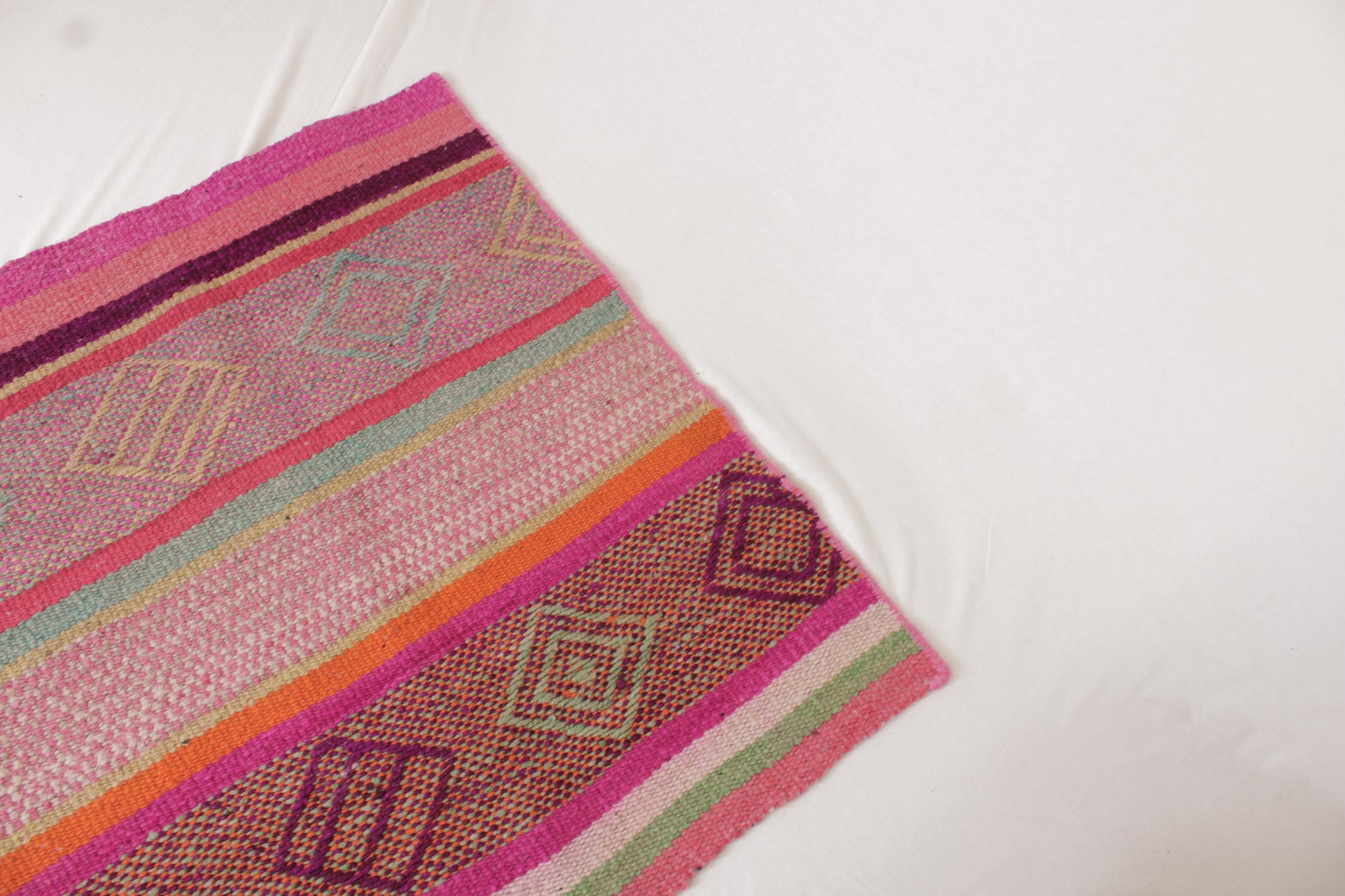Peruanischer Frazada-Läufer von Glueck & Fund, handgewebt, 135 x 74 cm, mit buntem Boho-Muster auf Holzfußboden.